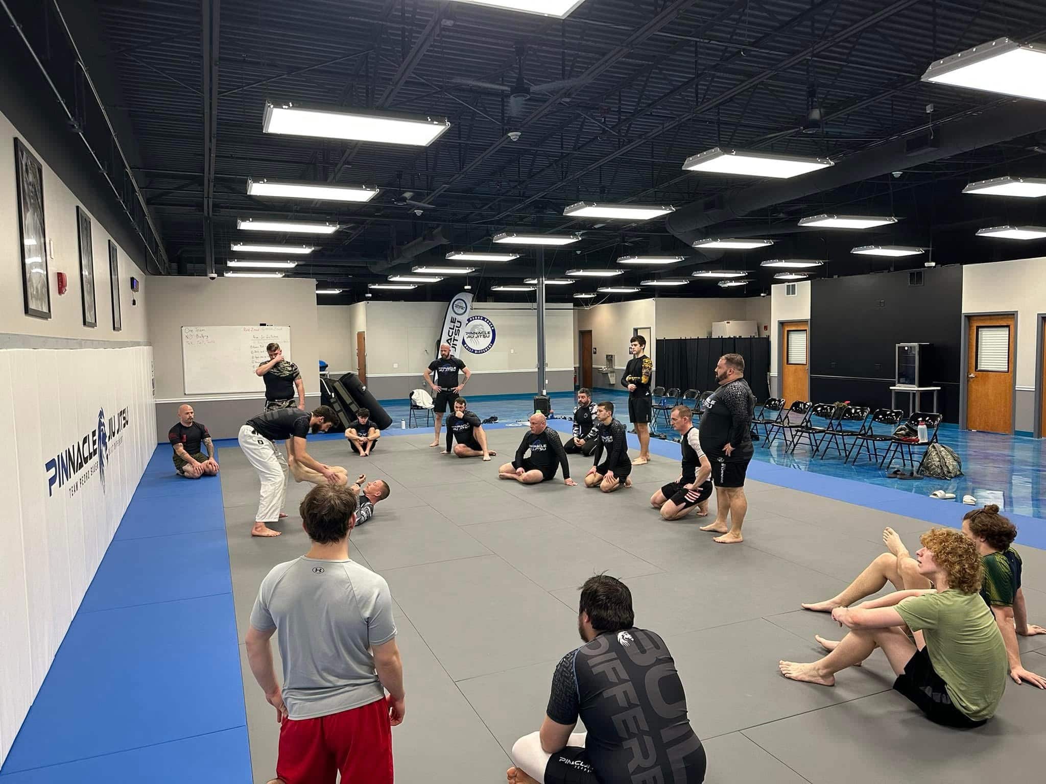pinnacle jiu jitsu no-gi class sitting on mats watching two students spar
